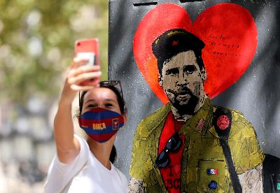 Seorang fans berswafoto dengan mural Lionel Messi berpakaian ala Che Guevara di  Barcelona, Spanyol, 30 Agustus 2020. REUTERS/Nacho Doce