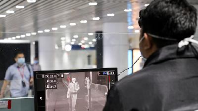 Petugas imigrasi Malaysia memeriksa suhu tubuh penumpang yang baru mendarat di bandara Sepang, Malaysia,  Maret 2020. Reuters/LLim Huey Teng