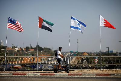 Warga melintas dengan latar bendera Amerika Serikat, Uni Emirat Arab, Israel and Bahrain di Israel, 14 September 2020. REUTERS/Nir Elias
