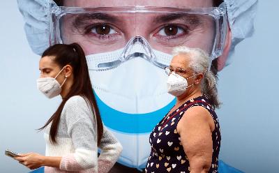 Warga beraktivitas dengan mengenakan masker saat melintasi  iklan klinik gigi di Madrid, Spanyol, 18 September 2020. REUTERS/Sergio Perez