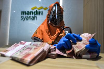 Petugas bank menghitung uang pecahan seratus ribu di Bank Mandiri Syariah di Jakarta, 28 September 2020. Tempo/Tony Hartawan