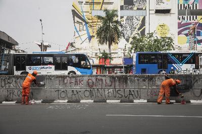 Petugas Penanganan Prasarana dan Sarana Umum (PPSU) membersihkan coretan  pasca unjuk rasa tolak UU Cipta Kerja  di Harmoni, Jakarta, 9 Oktober 2020. TEMPO/M Taufan Rengganis