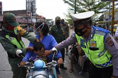 Petugas memakaikan masker pada warga saat operasi penegakan disiplin protokol kesehatan di Ciparay, Kabupaten Bandung, Jawa Barat, 29 September 2020. TEMPO/Prima Mulia