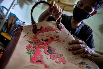 Pengerajin membuatan tas kulit bermotif pulau di Indonesia di bengkel kerja Janji Pertiwi, Jakarta, 3 November 2020. Tempo/Tony Hartawan