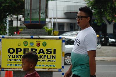 Pejalan kaki tanpa masker di depan papan Operasi Yustisi di kawasan Alun-Alun Bandung, Jawa Barat, 30 November 2020.  TEMPO/Prima Mulia