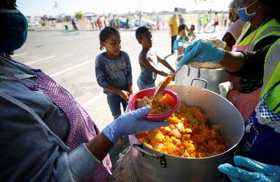 Anak-anak mengantri untuk mendapatkan makanan di kota Blue Downs dekat Cape Town, Afrika Selatan, 4 Mei 2020. Reuters/Mike Hutchings