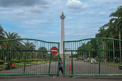 Petugas menutup gerbang Monumen Nasional (Monas) sesuai aturan penutupan area publik dan sejumlah tempat wisata selama libur Natal dan Tahun Baru di  Jakarta, 25 Desember 2020. TEMPO / Hilman Fathurrahman W