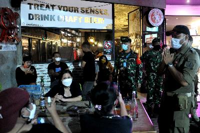 Petugas meminta pengunjung kafe untuk membubarkan diri karena telah melewati batas waktu jam malam yang ditentukan di kawasan Seminyak, Badung, Bali, 30 Desember 2020. ANTARA/Fikri Yusuf