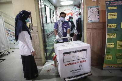 Petugas membawa kotak berisi Vaksin Covid-19 saat tiba di Puskesmas Kecamatan Cilincing, Jakarta Utara, 13 Januari 2021. TEMPO/M Taufan Rengganis