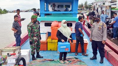 Petugas kesehatan (tengah) membawa kotak berisi vaksin COVID-19 Sinovac saat menumpang kapal penyeberangan tujuan wilayah terluar Pulau Aceh, di pelabuhan tradisional Lampulo, Banda Aceh, Aceh, 16 Januari 2021. ANTARA /Ampelsa
