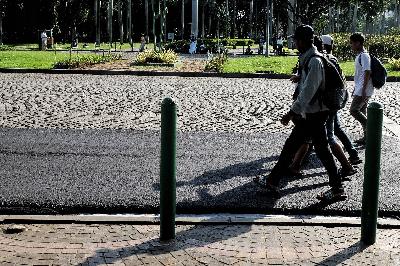 Pejalan kaki melintas di aspal yang pada tahap uji coba untuk digunakan dalam balap Formula E di Kawasan Monas, Medan Merdeka Timur, Jakarta, 22 Februari 2020. TEMPO / Hilman Fathurrahman W