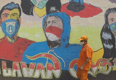 Petugas PPSU Tebet Timur menggambar mural melawan Covid-19 di sekitar Stasiun Cawang, Jakarta, 28 Desember 2020. TEMPO/Subekti