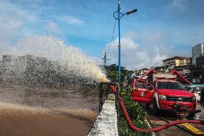 Mobil pemadam kebakaran memompa air luapan dari Kali Ciliwung di Jalan Raya Jatinegara Barat, Jakarta Timur, 8 Februari 2021. TEMPO / Hilman Fathurrahman W