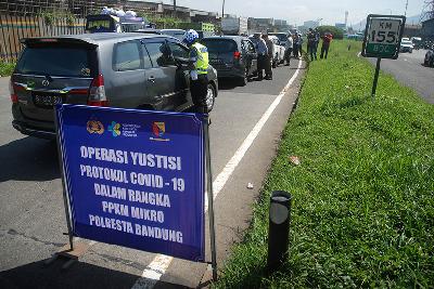 Polisi memeriksa kendaraan dari luar kota saat operasi PPKM  jelang libur Imlek di exit tol Cileunyi, Kabupaten Bandung, Jawa Barat, 11 Februari 2021. TEMPO/Prima Mulia