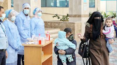 Seorang ibu dan anaknya tiba di klinik milik PBB, untuk mendapatkan vaksin covid-19 di Gaza, Palestina, 24 Februari 2021. Reuters/Mohammed Salem 