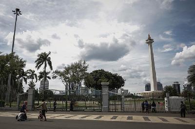 Warga berfoto di depan gerbang masuk Monumen Nasional (Monas), Jakarta, 3 Januari 2021. TEMPO/M Taufan Rengganis