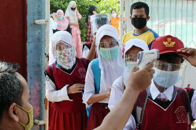 Guru memeriksa suhu tubuh siswa SD saat uji coba pembelajaran tatap muka di SDN Tegalwaru 02, Ciampea, Kabupaten Bogor, Jawa Barat, 15 Maret 2021. ANTARA/Arif Firmansyah