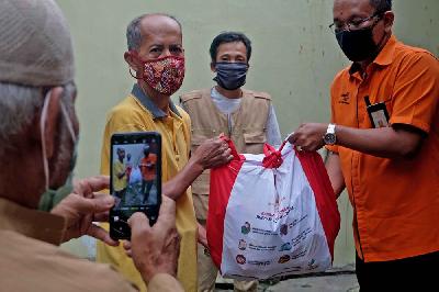 Petugas Pos Indonesia menyerahkan paket bantuan sosial (bansos) berupa  kebutuhan pokok (sembako) di Pasar Minggu, Jakarta, 28 April 2020. TEMPO/Nita Dian