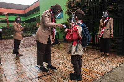 Guru memeriksa suhu tubuh siswa saat hari pertama uji coba pembelajaran tatap muka di SDN Kenari 08 pagi, Jakarta, 7 April 2021. TEMPO/Hilman Fathurrahman W