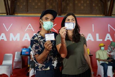 Vokalis grup band Slank Akhadi Wira Satriaji (Kaka Slank) bersama istri menunjukkan kartu vaksinasi usai menjalani vaksinasi COVID-19 di Galeri Nasional, Jakarta, 19 April 2021. TEMPO/Muhammad Hidayat