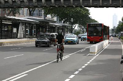 Pesepeda melintasi jalur khusus sepeda yang telah diberikan pembatas jalur permanen di Jalan Jenderal Sudirman, Jakarta, 26 Februari 2021.  TEMPO/Muhammad Hidayat