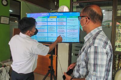 Petugas memberikan informasi kepada orang tua murid terkait pengajuan akun Penerimaan Peserta Didik Baru (PPDB) Tahun Pelajaran 2021/2022 di Sekolah SMA Negeri 87 Jakarta, 7 Juni 2021. TEMPO/Hilman Fathurrahman W