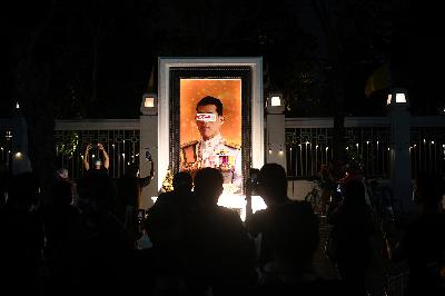 Sebuah stiker merusak potret Raja Thailand Maha Vajiralongkorn sebelum dihapus saat rapat umum menyerukan penggulingan pemerintahan Perdana Menteri Prayuth Chan-ocha dan reformasi monarki, di Bangkok, Thailand, 19 September 2020. REUTERS