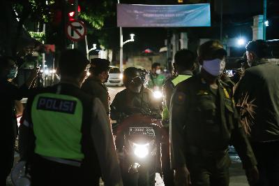 Polisi memeriksa pengendara motor saat penutupan jalan di Kemang Raya, Jakarta, dalam rangka pengetatan pembatasan kegiatan masyarakat (PPKM) mikro, 22 Juni 2021. TEMPO/M Taufan Rengganis