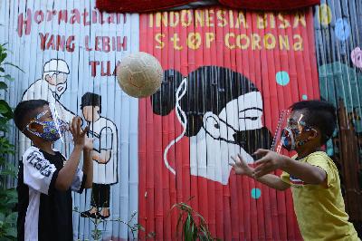 Anak-anak bermain di depan mural bertema Covid-19 di Kali Pasir, Jakarta, 28 Juli 2020.
TEMPO/Muhammad Hidayat