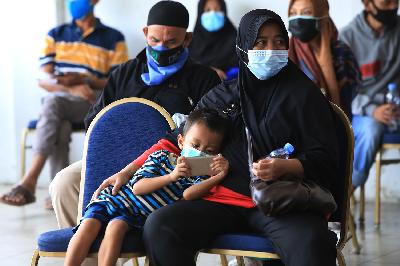 Warga membawa anaknya saat mengikuti vaksinasi Covid-19 untuk kelompok usia 18-50 tahun di GOR Ciracas, Jakarta, 28 Juni 2021. TEMPO/Subekti
