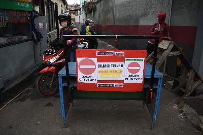 Pengendara motor melintasi sekat penutupan jalan masuk kampung saat PPKM Mikro di Cicadas, Bandung, Jawa Barat, 24 Juni 2021. TEMPO/Prima Mulia