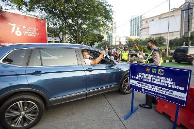 Seorang pengendara mobil menunjukkan surat undangan vaksin COVID-19 di Gelora Bung Karno, Senayan saat berlangsungnya Pemberlakuan Pembatasan Kegiatan Masyarakat (PPKM) Darurat di kawasan Bundaran Senayan, Jakarta, 3 Juli 2021.  ANTARA/M Risyal Hidayat
