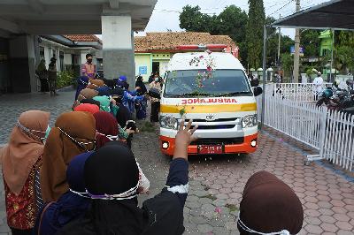 Sejumlah tenaga kesehatan memberikan penghormatan dengan menabur bunga ke mobil jenazah mendiang bidan Sri Wahyuni yang meninggal dunia akibat COVID-19 di Puskesmas Panarukan, Situbondo, Jawa Timur, 15 Juli 2021.  ANTARA/Seno