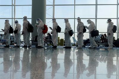 Penumpang pesawat menggunakan pakaian hazmat di Bandara Hong Kong, 9 Juli 2021. REUTERS/Thomas Peter