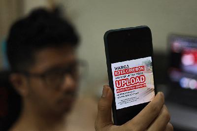 Warga menunjukan poster digital tentang himbauan untuk tidak mengunggah berita tentang Covid-19 yang diterima dari aplikasi WhatsApp di Jakarta, 18 Juni 2021. TEMPO/Nita Dian