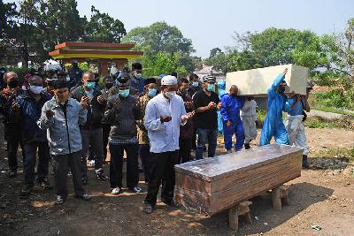 Keluarga dan kerabat tengah mendoakan jenazah saat rombongan lainnya menggotong peti di pemakaman khusus Covid-19 di Cikadut, Bandung, Jawa Barat, 19 Juli 2021. TEMPO/Prima mulia