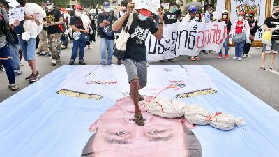 Demonstran menginjak gambar Perdana Menteri Thailand Prayuth Chan-ocha, saat menuntut pengunduran diri Prayuth Chan-ocha, terkait kebijakan vaksinasi di Bangkok, Thailand, 18 Juli. 2021. REUTERS/Chalinee Thirasupa