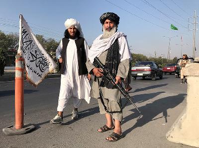 Seorang Taliban membawa M16 di luar kantor Menteri Dalam Negeri Afganistan di Kabul, 16 Agustus 2021. REUTERS