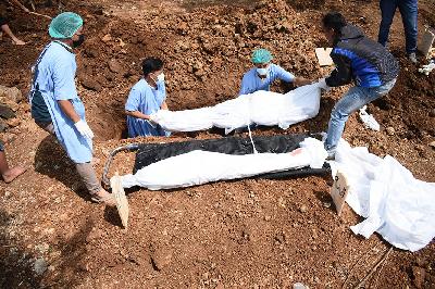 Petugas rumah sakit dan petugas pemakaman tanpa pakaian APD mengubur 2 jenazah dalam satu lubang di pemakaman Covid-19 di Bandung, Jawa Barat, 24 Agustus 2021. TEMPO/Prima Mulia