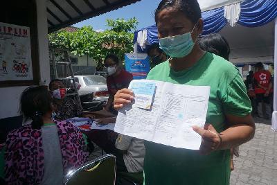 Seorang buruh warung tidak ber-KTP menunjukkan kartu vaksinasi di Gedung Serbaguna Puri Dwipari di Jalan Taman Siswa Kota Yogyakarta, 9 September 2021. TEMPO/Shinta Maharani