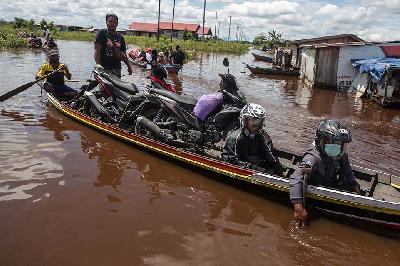 Pengendara motor melintasi banjir menggunakan perahu bermesin di jalan trans Kalimantan Bukit Rawi, Pulang Pisau, Kalimantan Tengah, 13 September 2021. ANTARA/Makna Zaezar