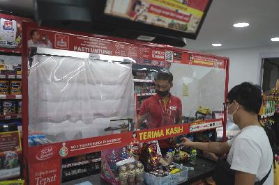 Karyawan melayani pelanggan dengan latar etalase rokok yang ditutup kain di salah satu minimarket di Jakarta, 14 September 2021. TEMPO/Muhammad Hidayat