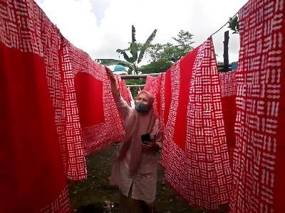 Enok Sukaesih, pemilik Agnesa Batik, memeriksa lembaran-lembaran kain batik yang dijemur di belakang rumah produksinya di Kampung Cigeureung, Kelurahan Nagarasari, Kecamatan Cipedes, Kota Tasikmalaya, Jawa Barat, 8 September 2021. TEMPO/Rommy Roosyana