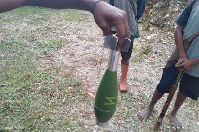 Warga memegang bom roket yang diduga ditembakkan aparat keamanan gabungan ke Distrik Kiwirok, Pegunungan Bintang, Papua. Foto: Istimewa

