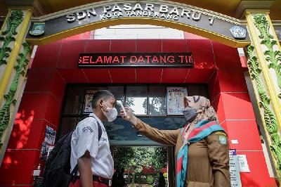Seorang guru mengukur suhu tubuh siswa sebelum memasuki lingkungan sekolah saat Pembelajaran Tatap Muka di SDN Pasar Baru 1, Kota Tangerang, Banten, 25 Oktober 2021. ANTARA/Fauzan