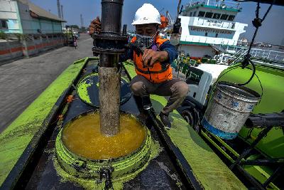 Pekerja tengah menlakukan pengisian minyak goreng dari lambung kapal ke dalam truk tangki di Pelabuhan Tanjung Priok, Jakarta.  Tempo/Tony Hartawan
