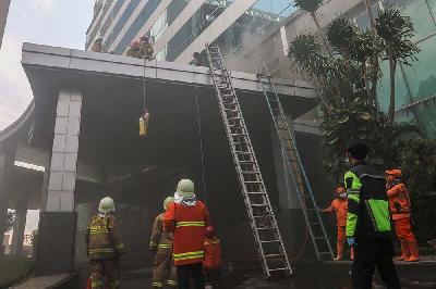 Petugas pemadam kebakaran saat memadamkan api yang membakar Gedung Cyber 1 di Mampang, Jakarta, 2 Desember 2021. TEMPO/Hilman Fathurrahman W