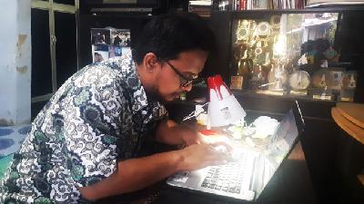Muhammad Baihaqi, mengoperasikan laptop di rumahnya di Kelurahan Kraton Lor Kota Pekalongan pada Kamis, 23 Desember 2021/TEMPO/  Jamal A. Nashr