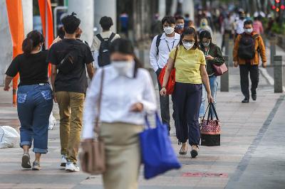 Warga menggunakan masker saat melintasi trotoar di Jalan Jenderal Sudirman, Jakarta, 29 November 2021. TEMPO/Hilman Fathurrahman W
