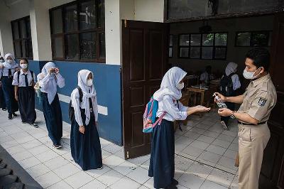 Guru memberikan cairan hand sanitizer pada siswa saat akan mengikuti Pembelajaran Tatap Muka Terbatas di SMPN 1 Depok, Jawa Barat, 4 Oktober 2021. TEMPO/M Taufan Rengganis